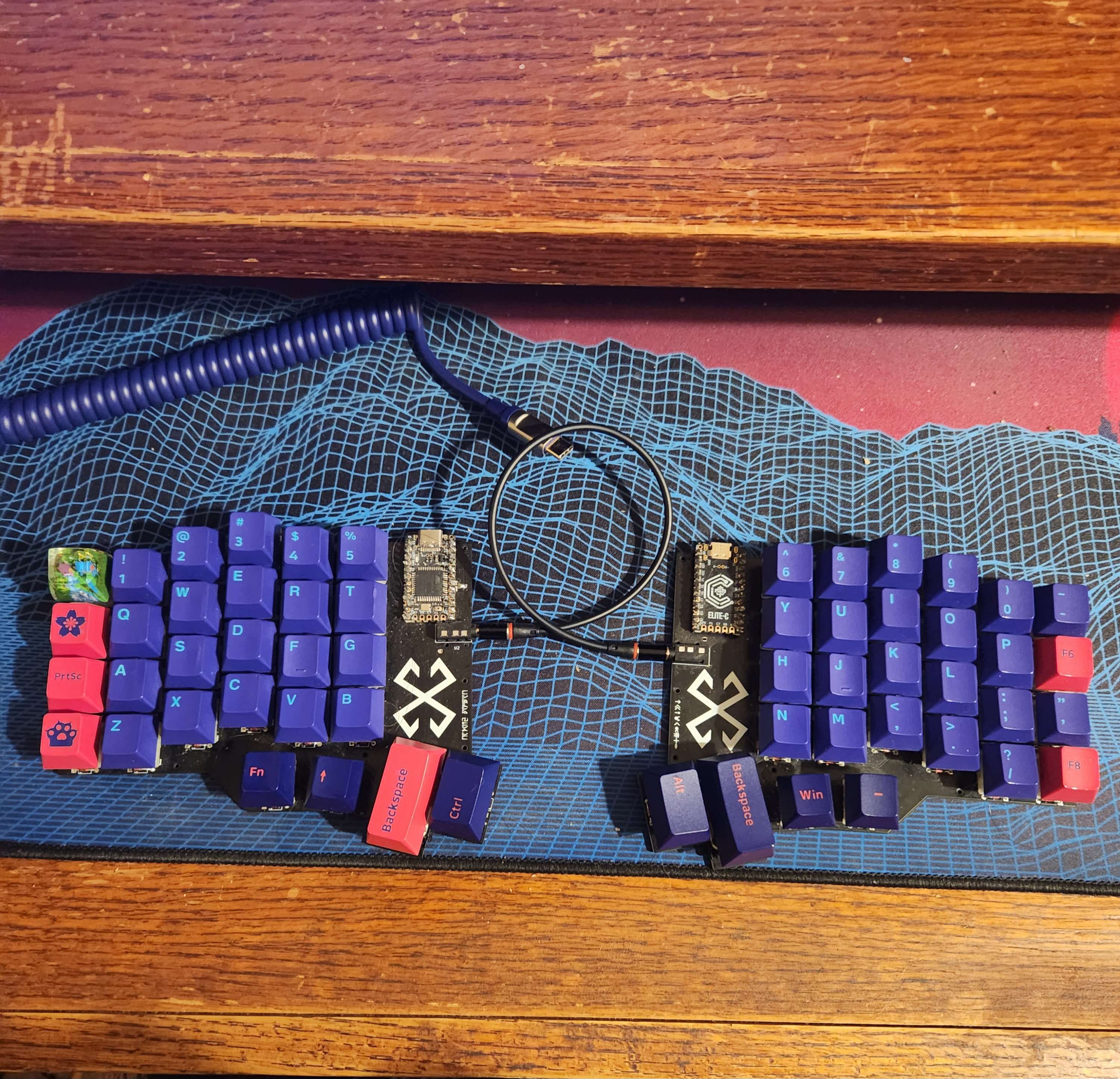 A split, column-staggered, ortholinear keyboard with AKKO Neon keycaps and an artisan mudkip keycap in the place of the grave and escape key.